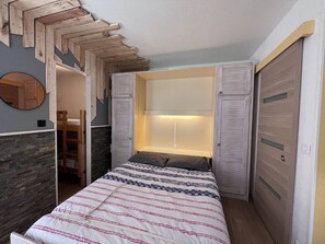 A bedroom with a bed, a wardrobe, a mirror, and a built-in bench.