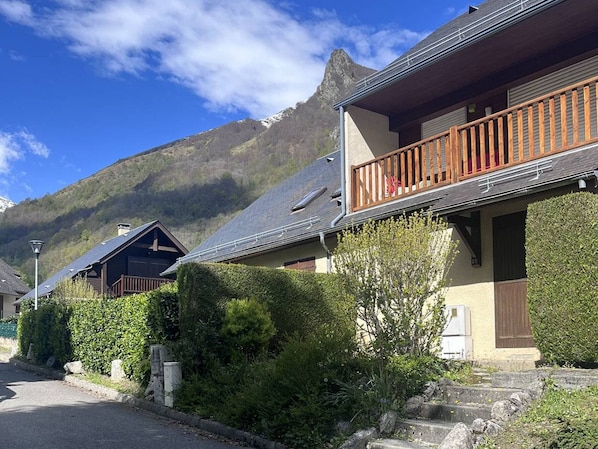 Eine Berglodge mit hölzerner Balkon, Steinstufen und Blick auf den Berg.