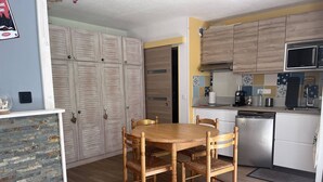 A compact kitchen with a dining table, chairs, a microwave, and a dishwasher. - Charming chalet for 4 in Cauterets with parking (Cauterets)
