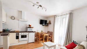 A compact living space with a kitchenette, dining area, and a sofa. - Apartment with Balcony and Wi-Fi in Cauterets Center (Cauterets)