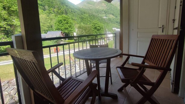 A balcony with a table and two wooden chairs, overlooking a mountainous landscape. - Apartment with Balcony and Wi-Fi in Cauterets Center (Cauterets)