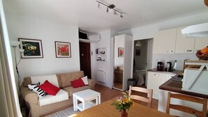A compact living space with a sofa, a dining table, and a kitchen area. - Apartment with Balcony and Wi-Fi in Cauterets Center (Cauterets)