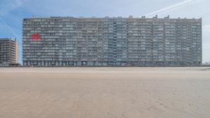 A large, multi-story hotel with a uniform facade, located adjacent to a sandy beach.