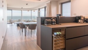 Una cocina moderna con un enfriador de vino empotrado, un comedor con vistas al mar y una zona de estar acogedora.