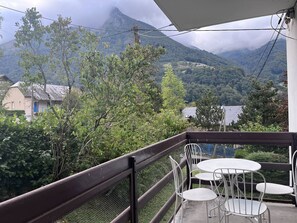 A balcony with a table and chairs overlooking a mountainous landscape. - Charming Apartment with Fireplace in Cauterets - Pets Allowed, Parking and Terrace (Cauterets)