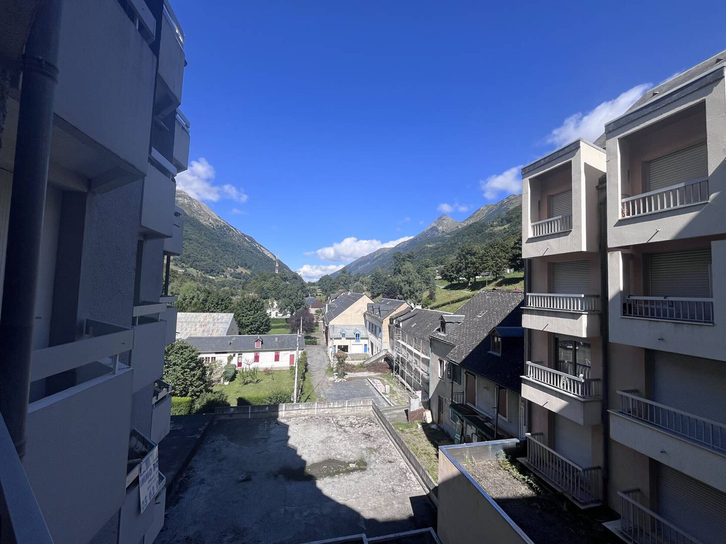 A residential area with multi-story buildings, a clear sky, and a mountainous backdrop.