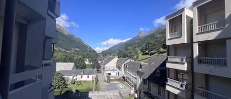 A residential area with multi-story buildings, a clear sky, and a mountainous backdrop.