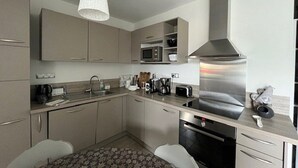 A modern kitchen with stainless steel appliances, a microwave, and a built-in oven. There is a dining area with a patterned table and chairs. - Elegant chalet in Cauterets center with terrace (Cauterets)
