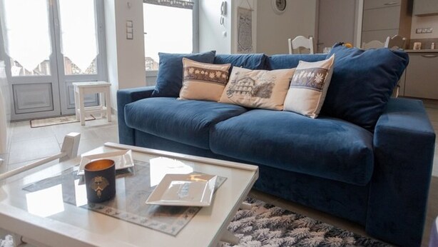 A modern living room with a blue sofa, a glass coffee table, and a patterned rug. - Elegant chalet in Cauterets center with terrace (Cauterets)