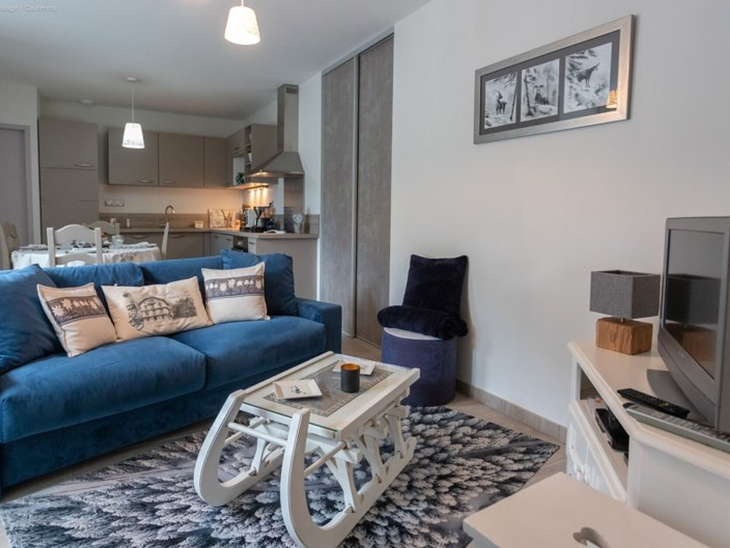 A modern living room with a blue sofa, a white coffee table, and a television on a stand.