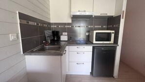A compact kitchen with a sink, a coffee maker, a microwave, and a refrigerator.