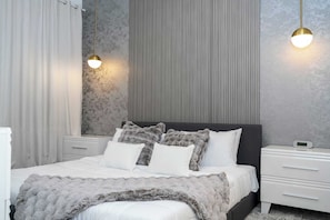 A modern bedroom with a bed, two bedside tables, a nightstand, and a wall-mounted light fixture. - Storey Lake 3BR | Sleeps 6 | Near Disney (Kissimmee)