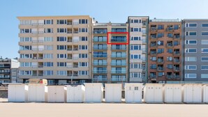 A row of multi-story buildings with balconies, a clear sky, and a sandy ground. - Apartment With a top Location in Mariakerke (Ostend)