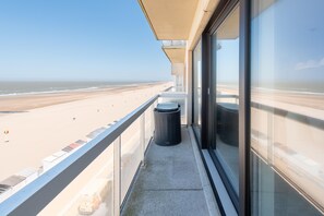 A balcony with a view of the beach, a trash bin, and a glass door. - Apartment With a top Location in Mariakerke (Ostend)