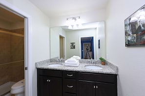 Une salle de bain avec deux lavabos, des meubles sombres, un miroir et un tableau encadré au mur.