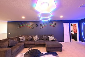 A living room with a sectional sofa, a coffee table, and a ceiling light fixture.