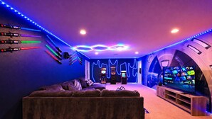 Una habitación con sofá, juegos de arcade y televisor.