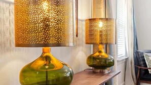 Two lamps on a wooden console table, a framed artwork on the wall, and a chair with a cushion in the background. - Family-Friendly 4BR w/ Fenced Yard & Parking (Durham)