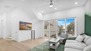 A spacious living room with a large window, a painting on the wall, and a green rug. - Luxury 3BR 3BA Home with Parking & Downtown Views (Houston)