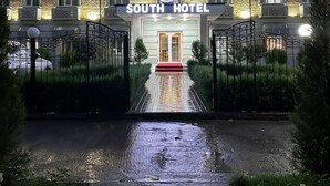 A hotel entrance with a stone facade, a red carpet, and a gated driveway. - South Hotel Tashkent  (Tashkent)