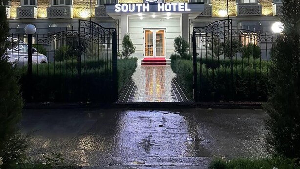 A hotel entrance with a stone facade, a red carpet, and a gated driveway. - South Hotel Tashkent  (Tashkent)