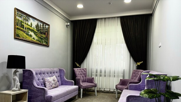 A room with a purple sofa, two matching armchairs, a small table with a lamp, and a painting on the wall. - South Hotel Tashkent  (Tashkent)