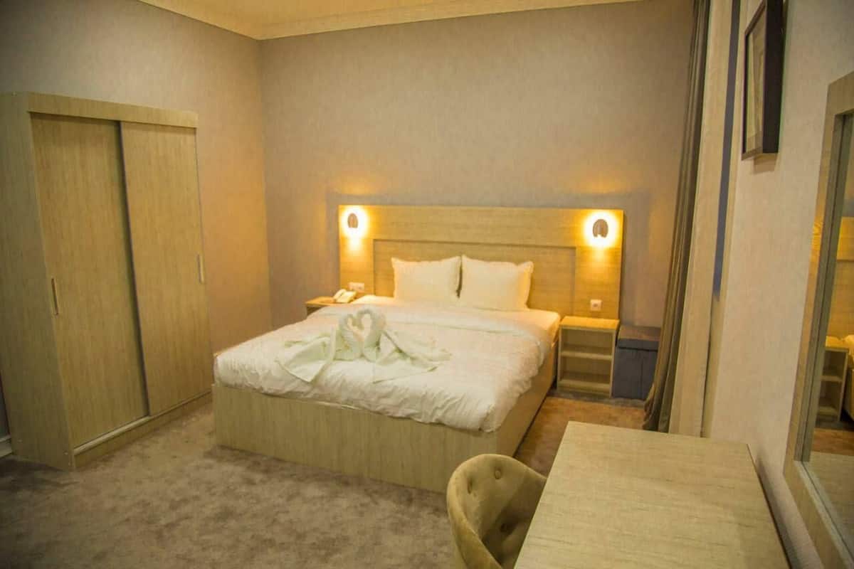 Une chambre d’hôtel comprenant un lit, des tables de chevet, un bureau et une armoire.