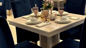 A dining area with tables set for four, each with a vase of flowers, wine glasses, and plates. - South Hotel Tashkent  (Tashkent)
