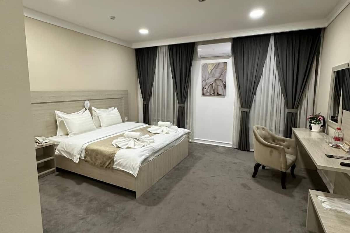 Une chambre d’hôtel moderne, dotée d’un grand lit, d’un bureau et d’une chaise.