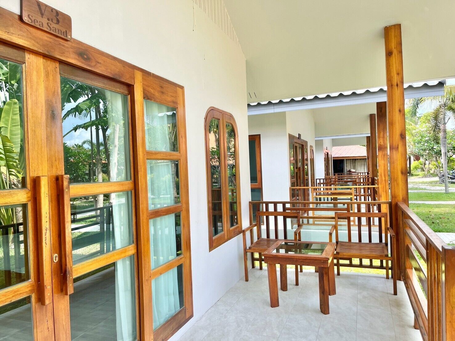 A wooden-framed room with large windows, a tiled floor, and a view of a garden.