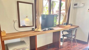 A room with a wooden desk, a television, a small refrigerator, and a chair. - Sea Beach at Lipe (Koh Lipe)