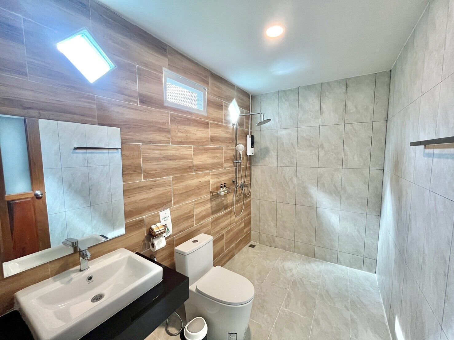 A modern bathroom with a large mirror, a sink, a toilet, and a shower area.