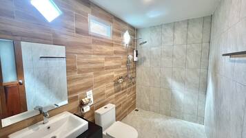 A modern bathroom with a large mirror, a sink, a toilet, and a shower area.