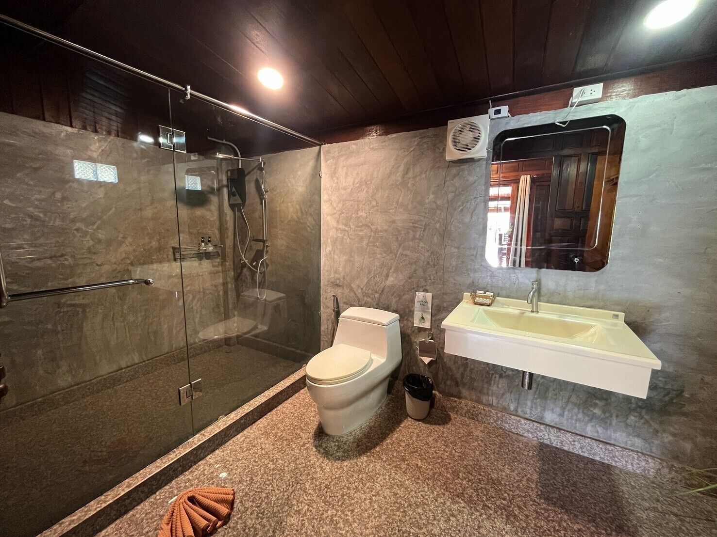Un baño moderno con ducha de vidrio, inodoro y lavamanos con espejo.