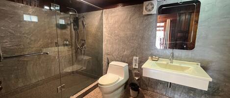 Un baño moderno con ducha de vidrio, inodoro y lavamanos con espejo.