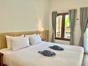 A hotel room with a large bed, two pillows, a bedside lamp, and a window with curtains. - Sea Beach at Lipe (Koh Lipe)