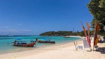 Una playa con barcos, un cartel y un cielo despejado.