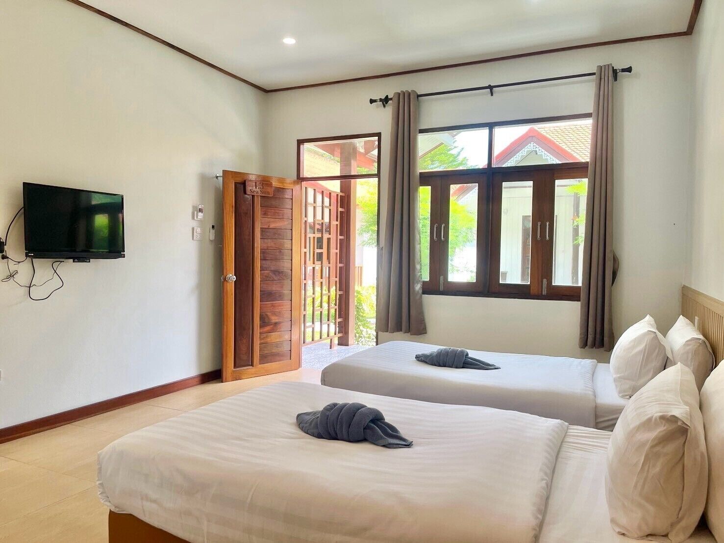 Quarto de hotel com duas camas, televisão e vista para o exterior.