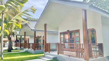 A two-story building with a covered porch and a small garden area with palm trees.