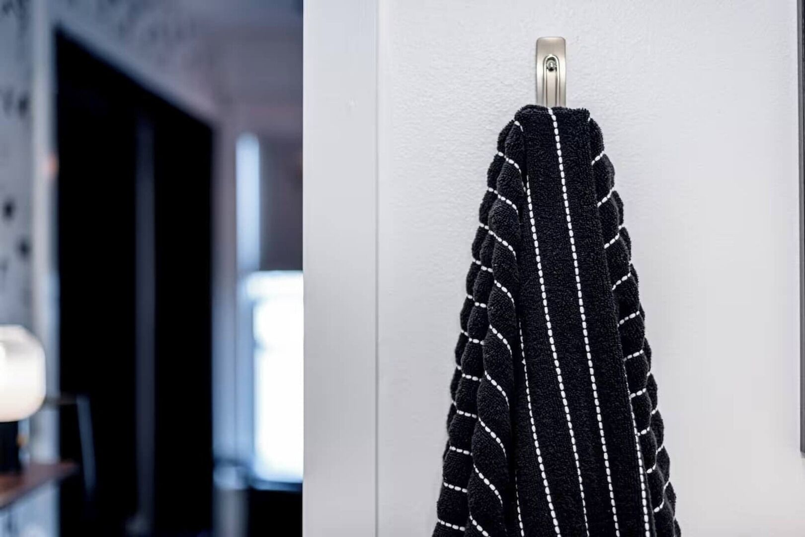 A black towel with white stitching hanging on a hook.