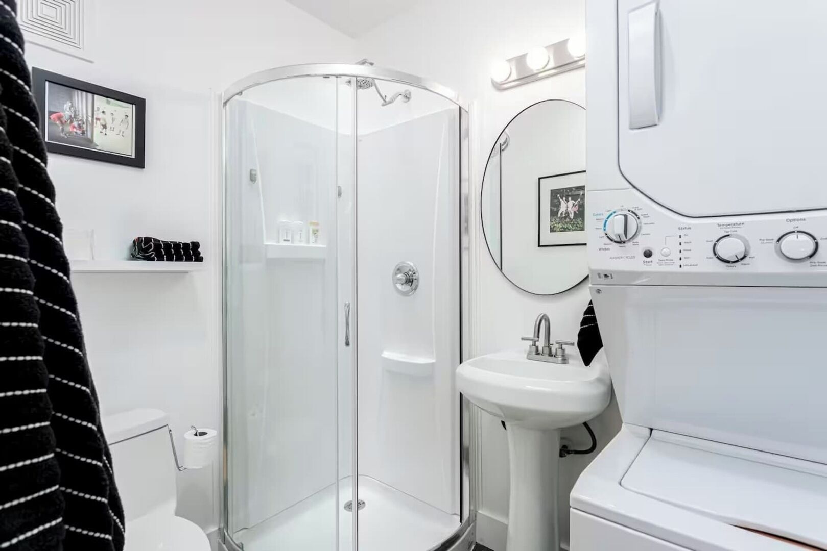 Een moderne badkamer met een douchecabine van glas, een witte wastafel en een ingebouwde wasmachine.