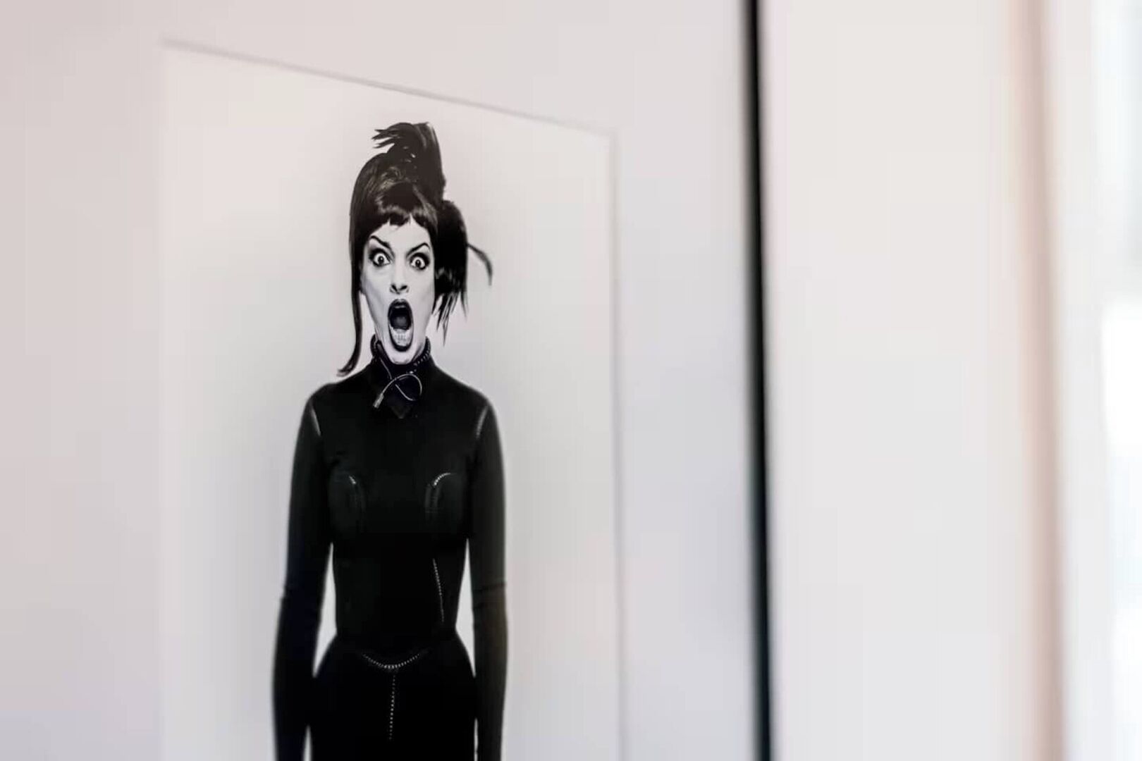 A framed artwork of a figure in a black outfit with a high collar and a chain detail.