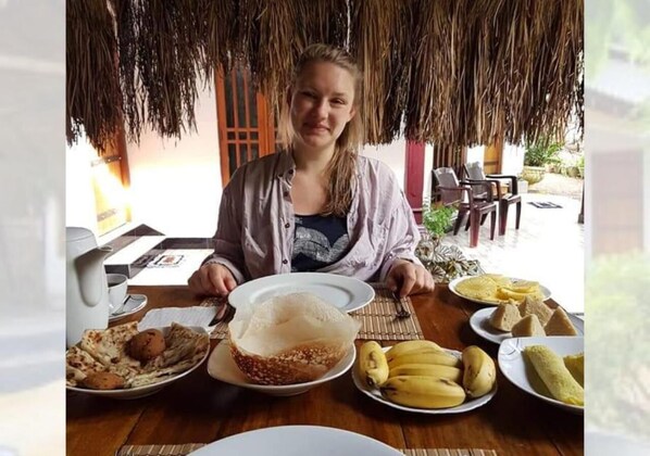 A person seated at a table with various food items, including bananas and a bowl of rice. - Ivory Safari House (udawalawa)