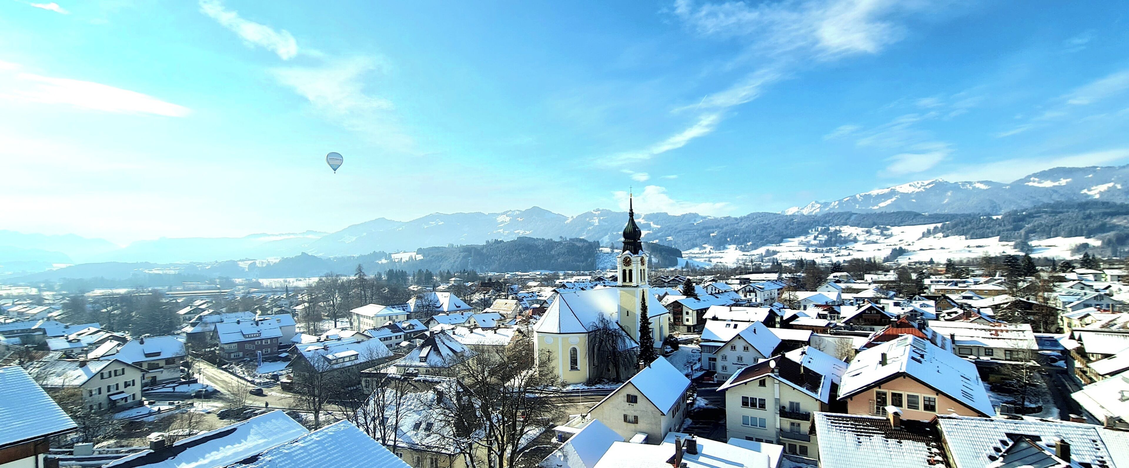 En stad med snötäckta byggnader, en framträdande kyrka med ett klocktorn och en klar himmel.