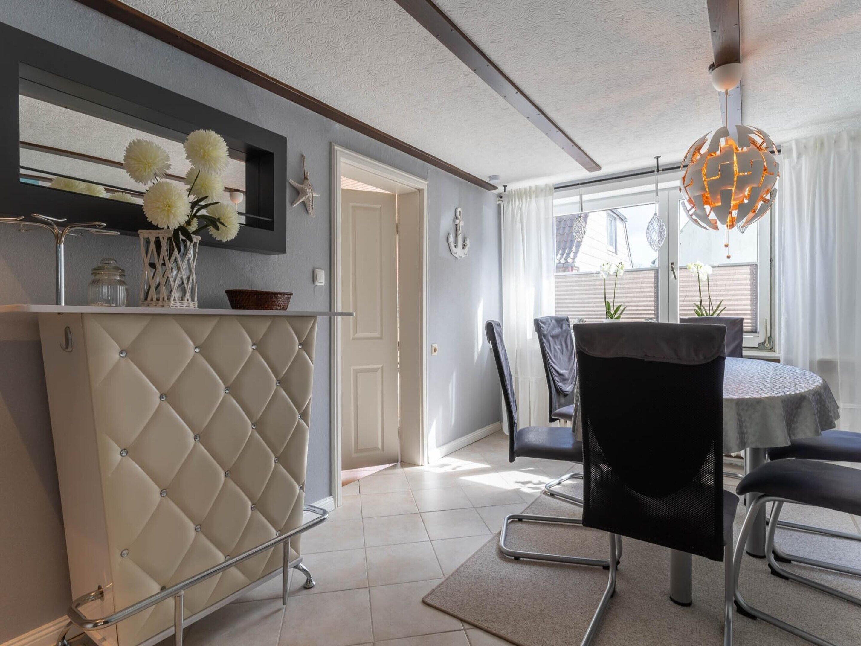 A modern kitchen with a white cabinet, a dining area with a table and chairs, and a view of the outside.
