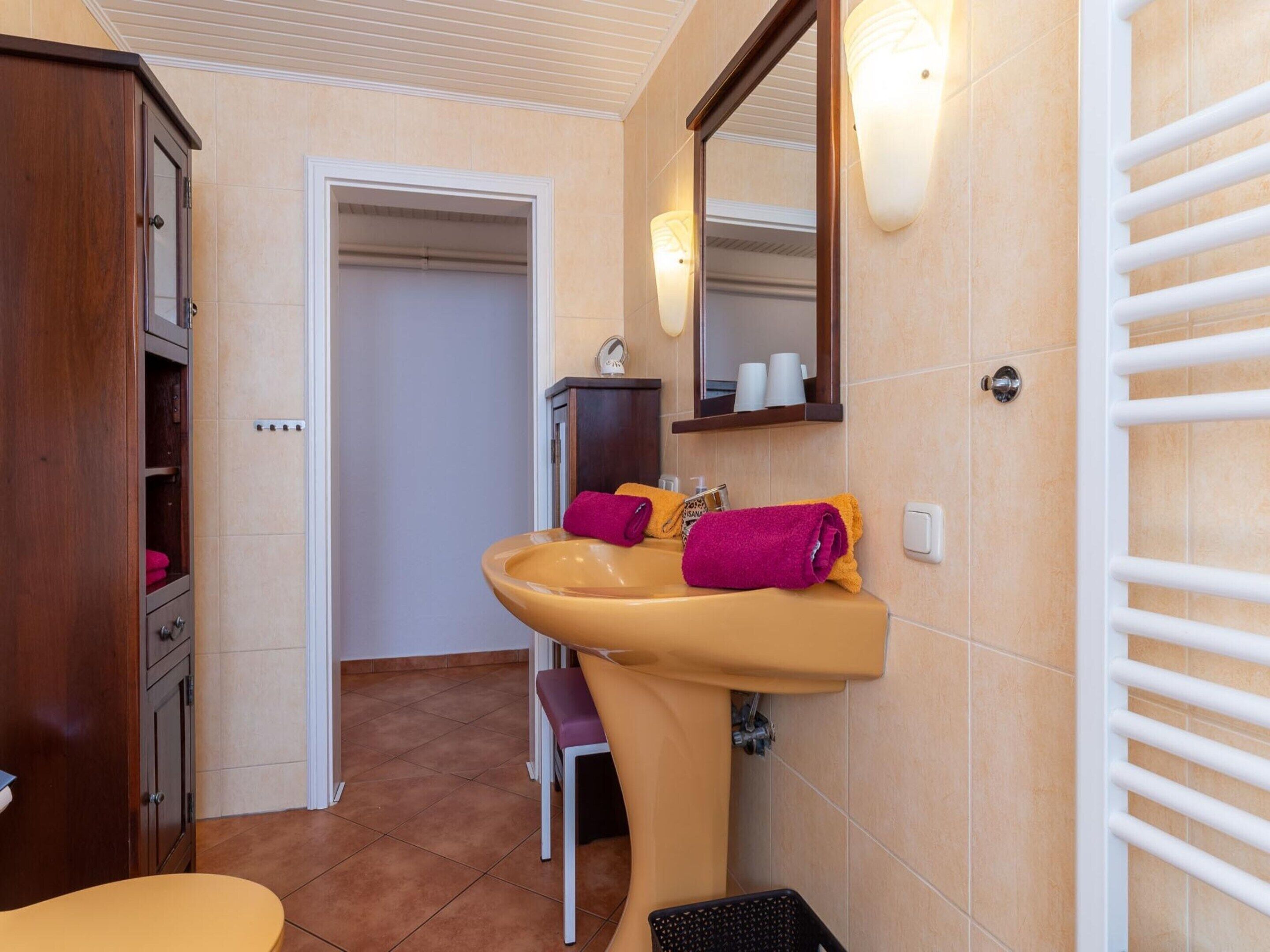 Une salle de bain équipée d’un lavabo, d’un miroir, d’un porte-serviettes et d’un meuble en bois.