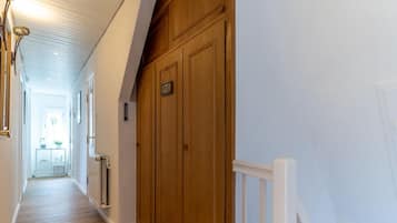 Um corredor com piso de madeira, corrimão branco e uma porta com a inscrição 'PRIVATE'.