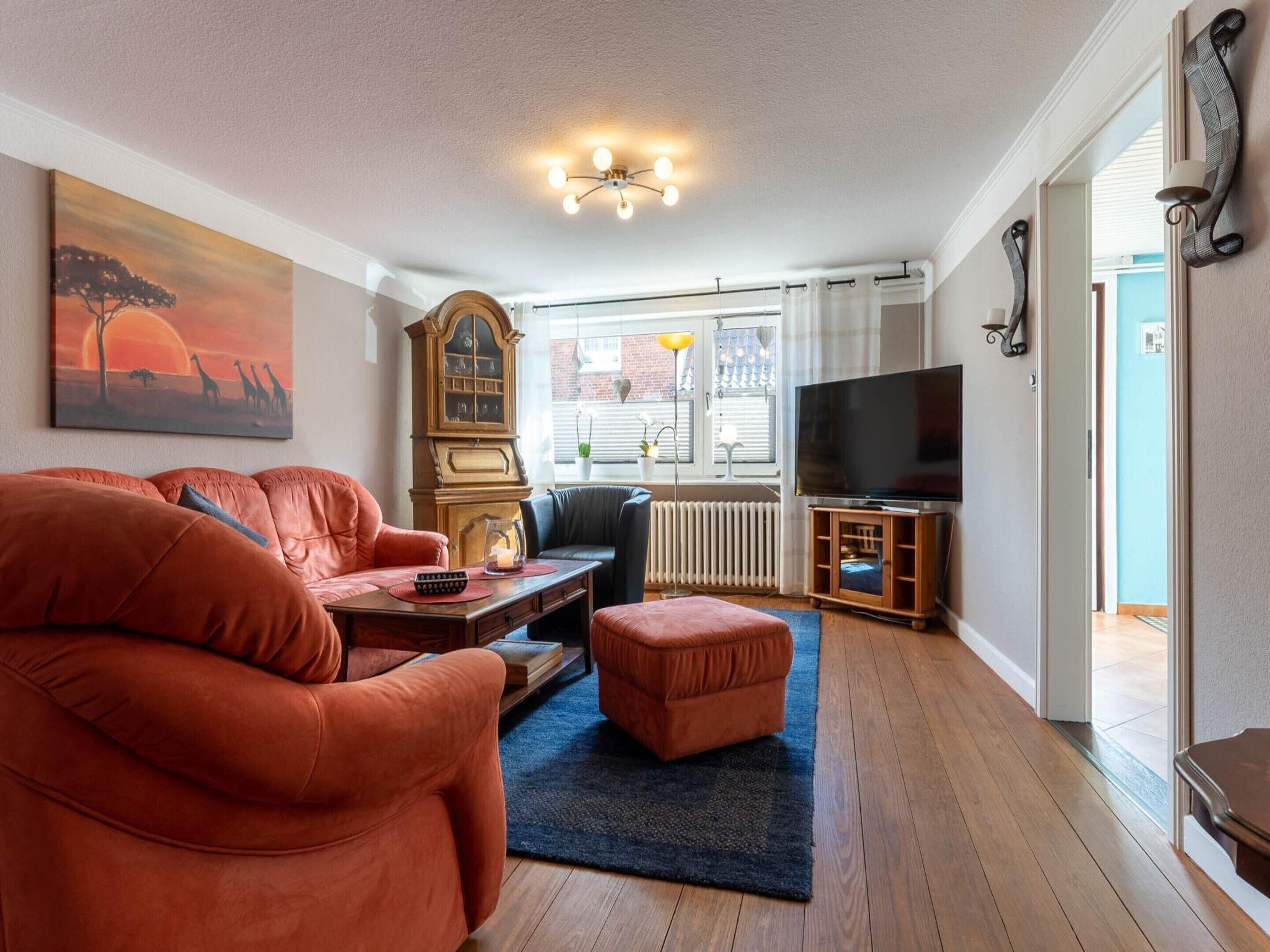 A living room with a sofa, a coffee table, a television, and a painting on the wall.