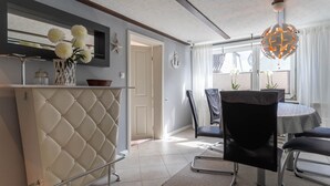 A modern kitchen with a white countertop, a hanging light fixture, and a dining area with a round table and chairs. - Ferienhaus in Tonning (Toenning)