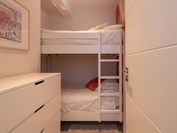 Ein Schlafraum mit Etagenbetten, einem weißen Kleiderschrank und einem kleinen Schreibtisch.